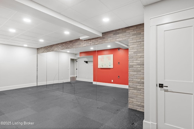 basement with a drop ceiling and brick wall