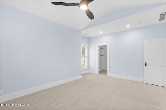 empty room featuring lofted ceiling, light colored carpet, and ceiling fan