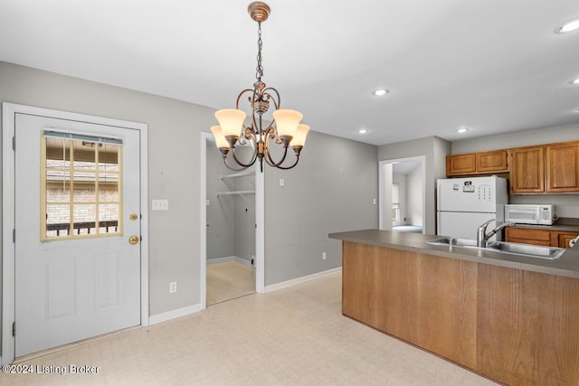 kitchen with kitchen peninsula, white appliances, sink, pendant lighting, and an inviting chandelier