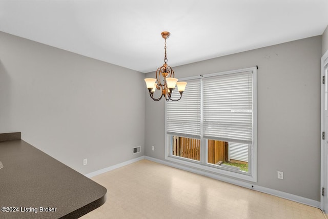 unfurnished dining area featuring a chandelier