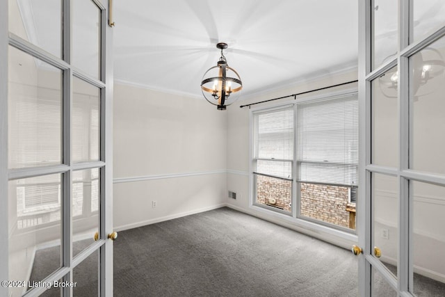 empty room featuring dark colored carpet, french doors, and ornamental molding