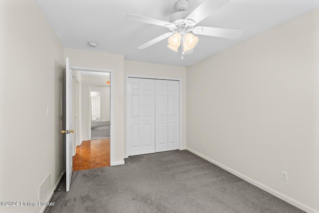 unfurnished bedroom featuring ceiling fan, dark carpet, and a closet