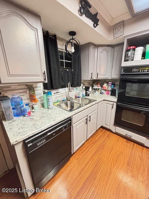 kitchen featuring tasteful backsplash, gray cabinetry, sink, black appliances, and light hardwood / wood-style flooring