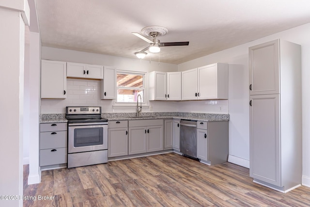 kitchen featuring appliances with stainless steel finishes, dark hardwood / wood-style flooring, tasteful backsplash, ceiling fan, and sink