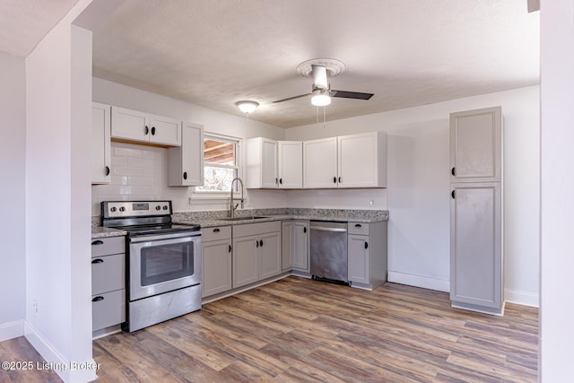 kitchen with dark wood-type flooring, sink, ceiling fan, white cabinetry, and stainless steel appliances