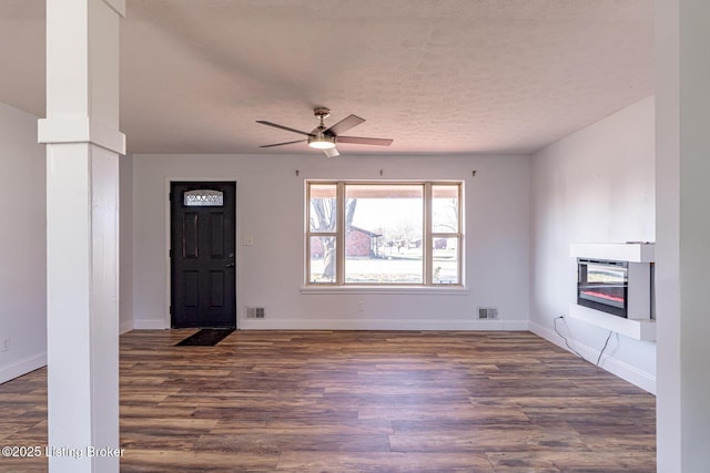 foyer entrance featuring a textured ceiling, ceiling fan, and dark wood-type flooring