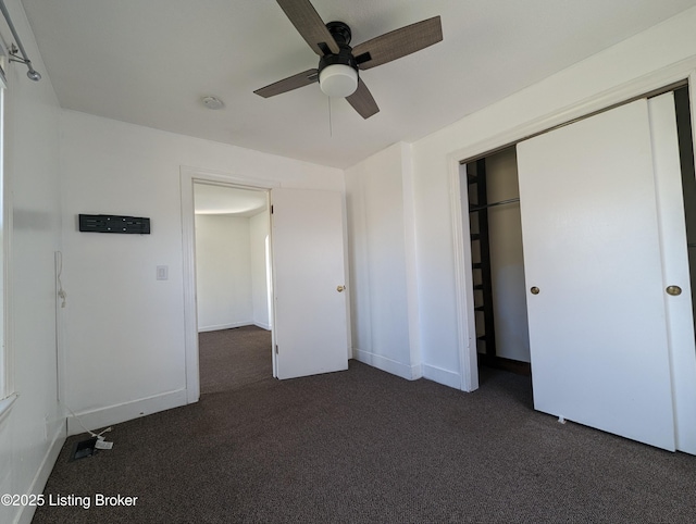 unfurnished bedroom with ceiling fan, a closet, and dark colored carpet