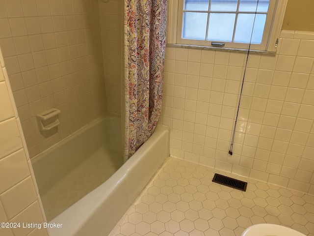 bathroom with tile patterned floors, toilet, and tile walls