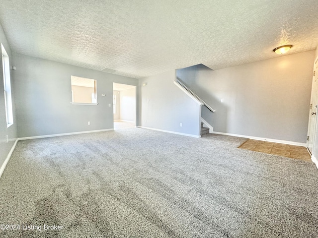 unfurnished living room featuring carpet and a textured ceiling