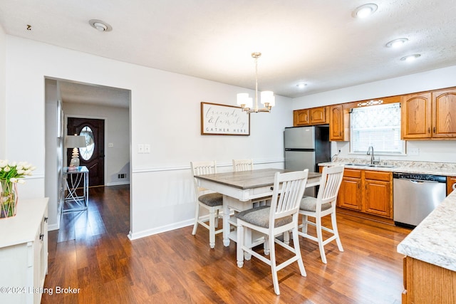 kitchen with stainless steel appliances, sink, pendant lighting, a notable chandelier, and dark hardwood / wood-style floors