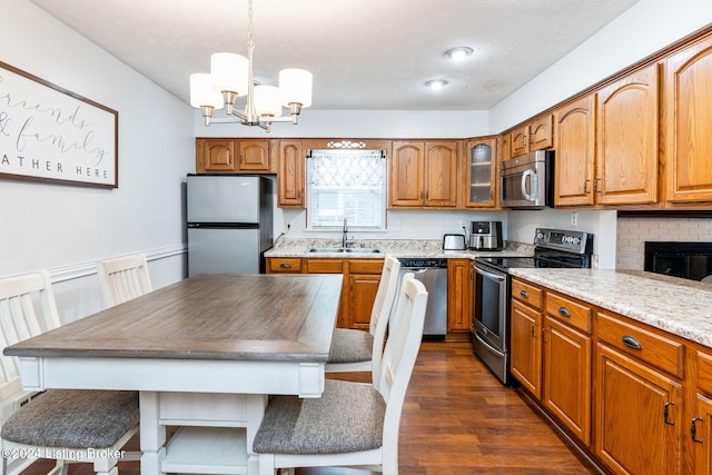 kitchen featuring sink, stainless steel appliances, dark hardwood / wood-style flooring, a notable chandelier, and pendant lighting