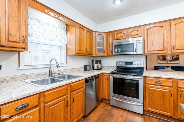 kitchen featuring appliances with stainless steel finishes, dark hardwood / wood-style flooring, a textured ceiling, and sink