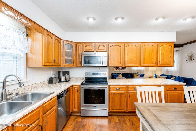 kitchen featuring sink, ornamental molding, a textured ceiling, dark hardwood / wood-style flooring, and stainless steel appliances