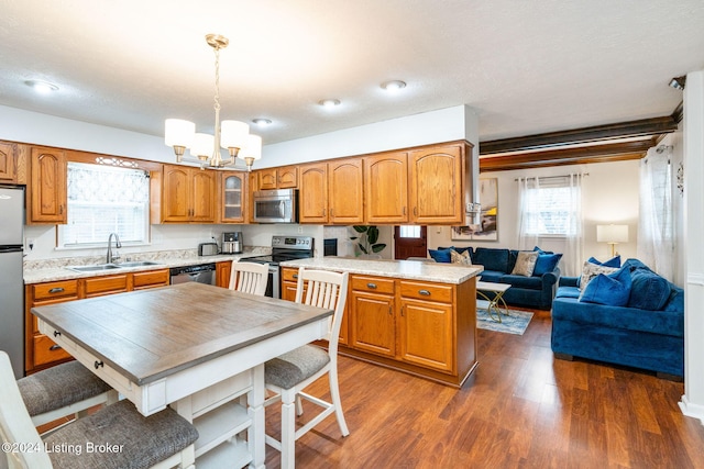 kitchen with sink, dark wood-type flooring, a notable chandelier, decorative light fixtures, and appliances with stainless steel finishes