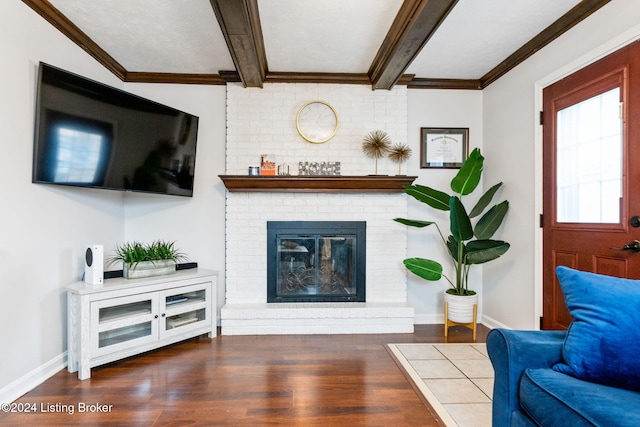 living room with beam ceiling, dark hardwood / wood-style flooring, crown molding, and a brick fireplace