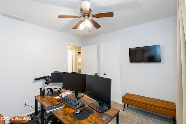 carpeted home office featuring ceiling fan and a textured ceiling