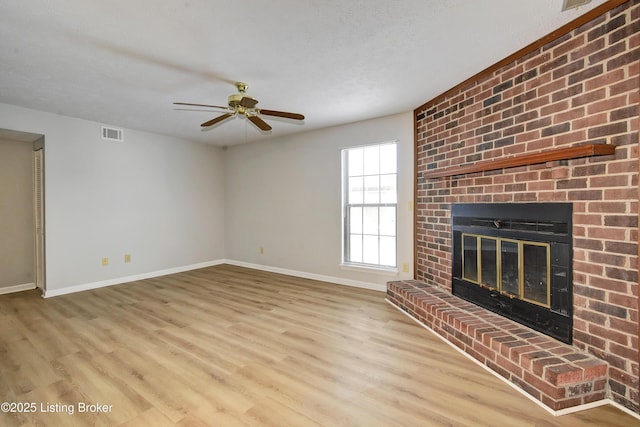 unfurnished living room with ceiling fan, a fireplace, and light wood-type flooring