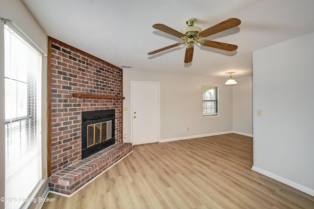 unfurnished living room featuring a brick fireplace, light hardwood / wood-style flooring, and ceiling fan