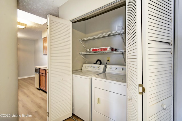 clothes washing area featuring washer and clothes dryer, light hardwood / wood-style floors, and a textured ceiling