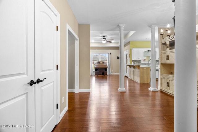 interior space featuring ornate columns, a raised ceiling, sink, a chandelier, and dark hardwood / wood-style floors