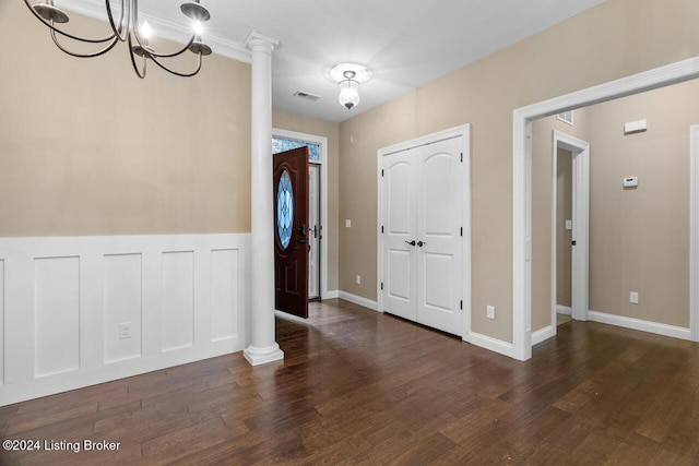 foyer with ornate columns, dark hardwood / wood-style flooring, and a chandelier