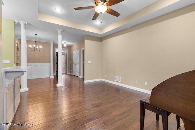 living room featuring a raised ceiling, ornate columns, dark hardwood / wood-style floors, and ceiling fan with notable chandelier