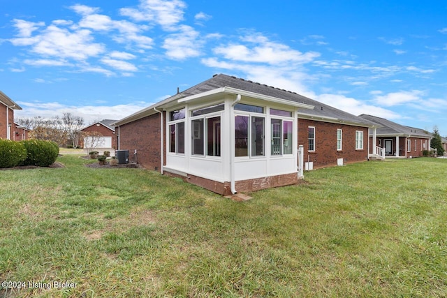 view of side of property featuring a yard, a garage, a sunroom, and central air condition unit