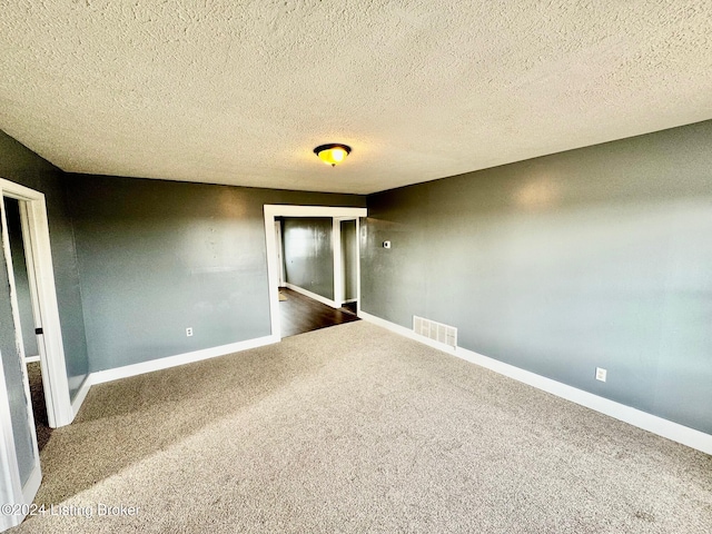 carpeted empty room featuring a textured ceiling