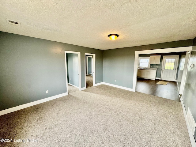 carpeted empty room with a textured ceiling