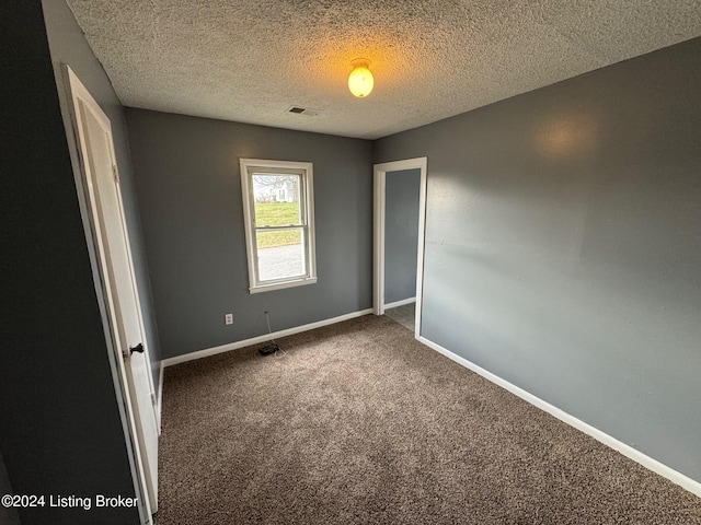 carpeted empty room featuring a textured ceiling