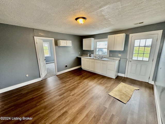 kitchen featuring white cabinets, light wood-type flooring, sink, and a textured ceiling