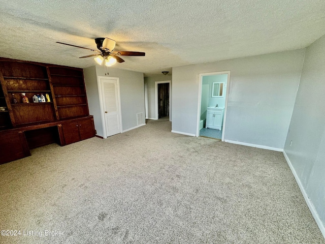 unfurnished bedroom featuring ensuite bath, ceiling fan, light colored carpet, and a textured ceiling