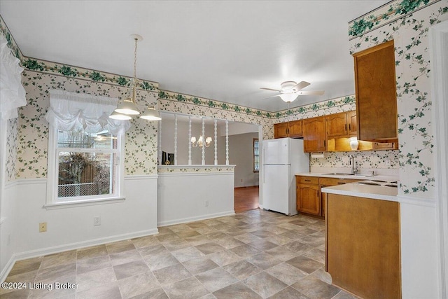 kitchen featuring decorative light fixtures, white refrigerator, sink, and ceiling fan