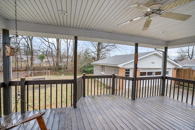 wooden terrace with an outbuilding, a garage, ceiling fan, and a lawn