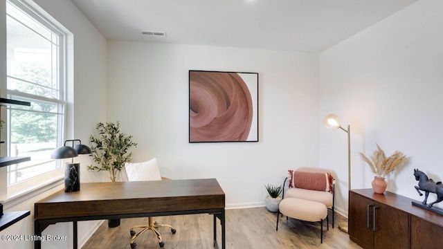 home office with light wood-type flooring and a healthy amount of sunlight