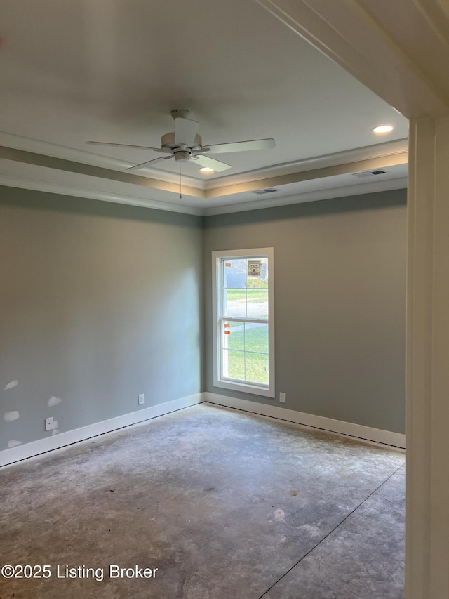 spare room featuring concrete floors, a tray ceiling, and ceiling fan