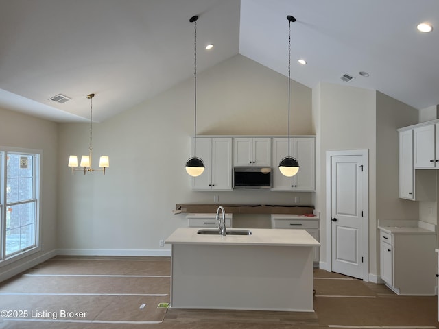 kitchen featuring white cabinetry, sink, an inviting chandelier, pendant lighting, and an island with sink