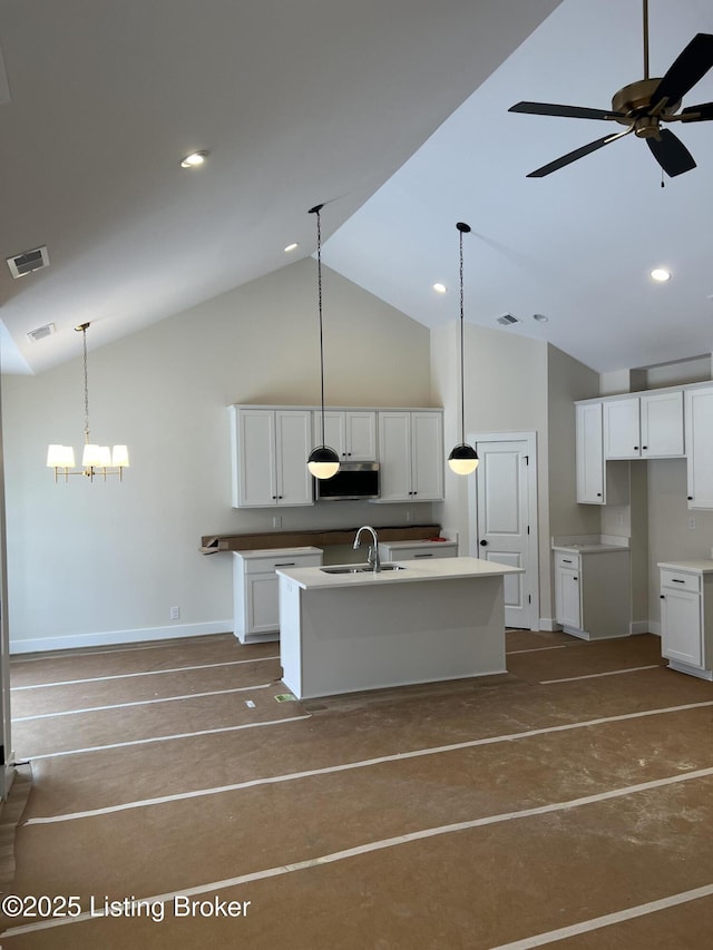 kitchen with ceiling fan, sink, decorative light fixtures, white cabinetry, and an island with sink