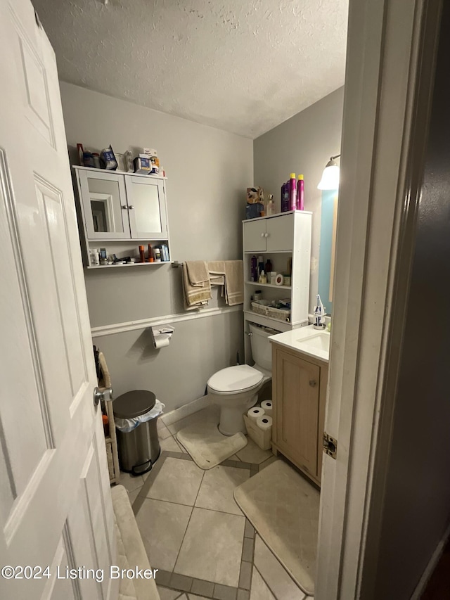 bathroom with toilet, vanity, a textured ceiling, and tile patterned floors