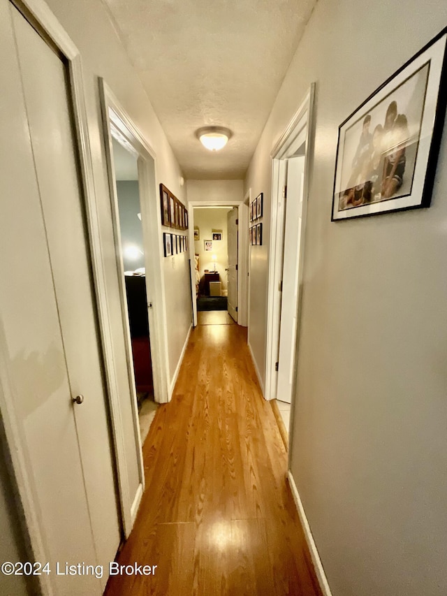 hall featuring a textured ceiling and light hardwood / wood-style flooring