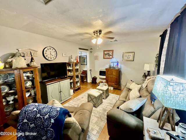 living room featuring ceiling fan, a textured ceiling, and light hardwood / wood-style flooring