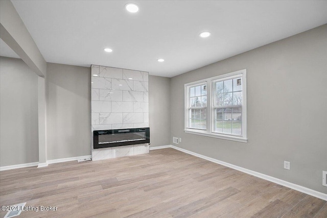 unfurnished living room with light hardwood / wood-style flooring and a tiled fireplace