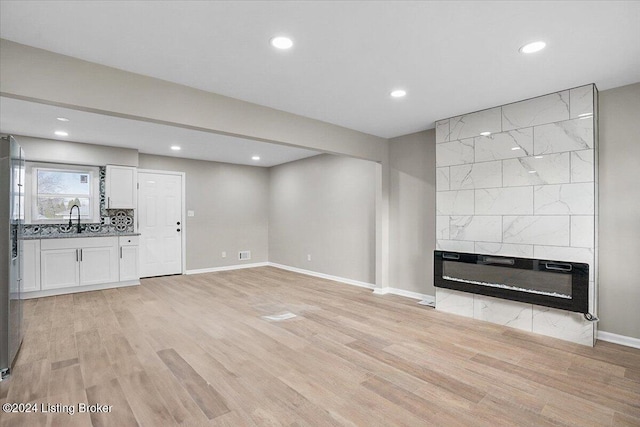 unfurnished living room featuring a fireplace, light wood-type flooring, and sink