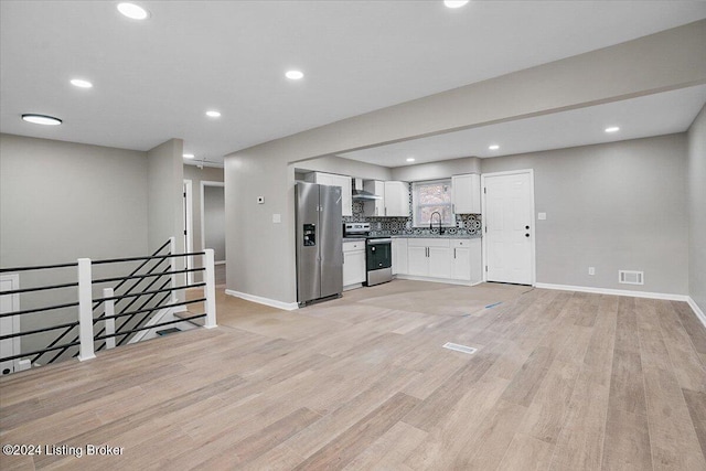 kitchen featuring appliances with stainless steel finishes, backsplash, light hardwood / wood-style flooring, and white cabinetry