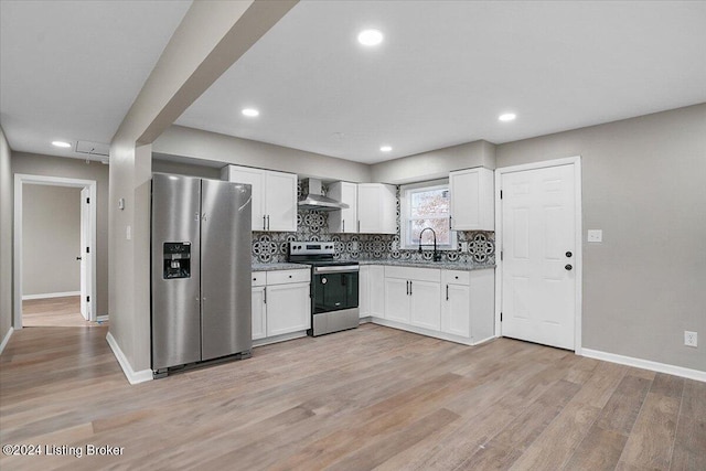 kitchen featuring sink, wall chimney exhaust hood, light wood-type flooring, white cabinetry, and stainless steel appliances