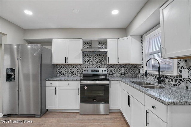 kitchen featuring white cabinets, wall chimney exhaust hood, sink, and appliances with stainless steel finishes