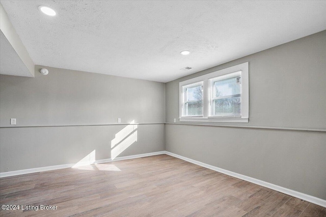 unfurnished room with a textured ceiling and light hardwood / wood-style flooring