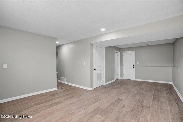 empty room with light hardwood / wood-style flooring and a textured ceiling