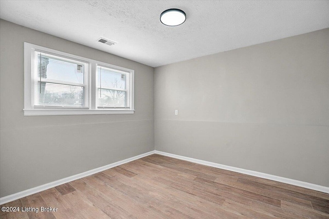 spare room featuring a textured ceiling and light wood-type flooring