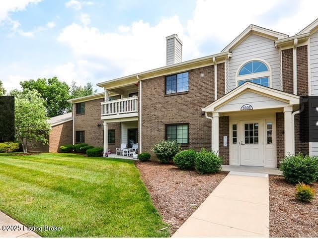 view of front of house with a balcony and a front yard